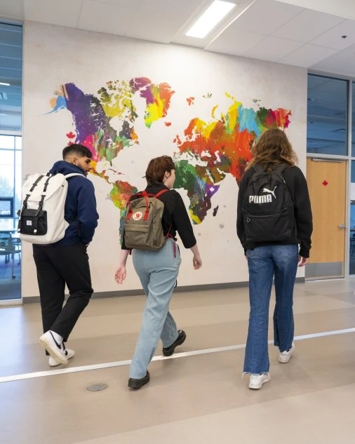 Students walking through a university building with a world map on the wall behind them, representing CIFAL Victoria's fourth pillar of innovation and entrepreneurship.
