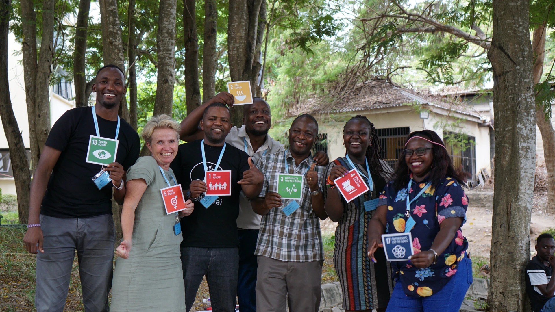 Participants from the 2022 CBPR Autumn School with ICLD in Dar es Salaam, Tanzania pose as a group holding postcards showing the UN Sustainable Development Goals.