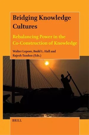 Book cover of "Bridging Knowledge Cultures: Rebalancing Power in the co-Construction of Knowledge" by Walter Lepore, Budd Hall, and Rajesh Tandon. The cover is orange, and features an image with someone in silhouete pushing a boat with a pole, and a bridge in the background.