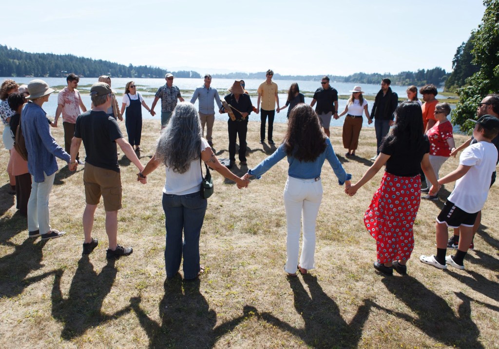 Members of the Balance Co-Lab with representatives from T'Sou-ke First Nation and collaborators from the University of Victoria, standing in a circle holding hands outside.