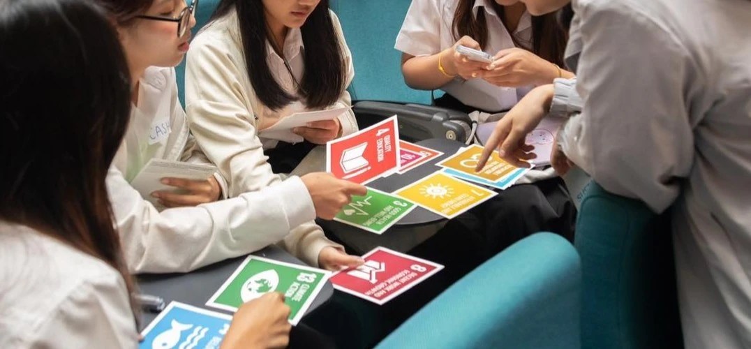 Students sitting in lecture theatre seats holding cards showing the symbols representing the UN Sustainable Development Goals.