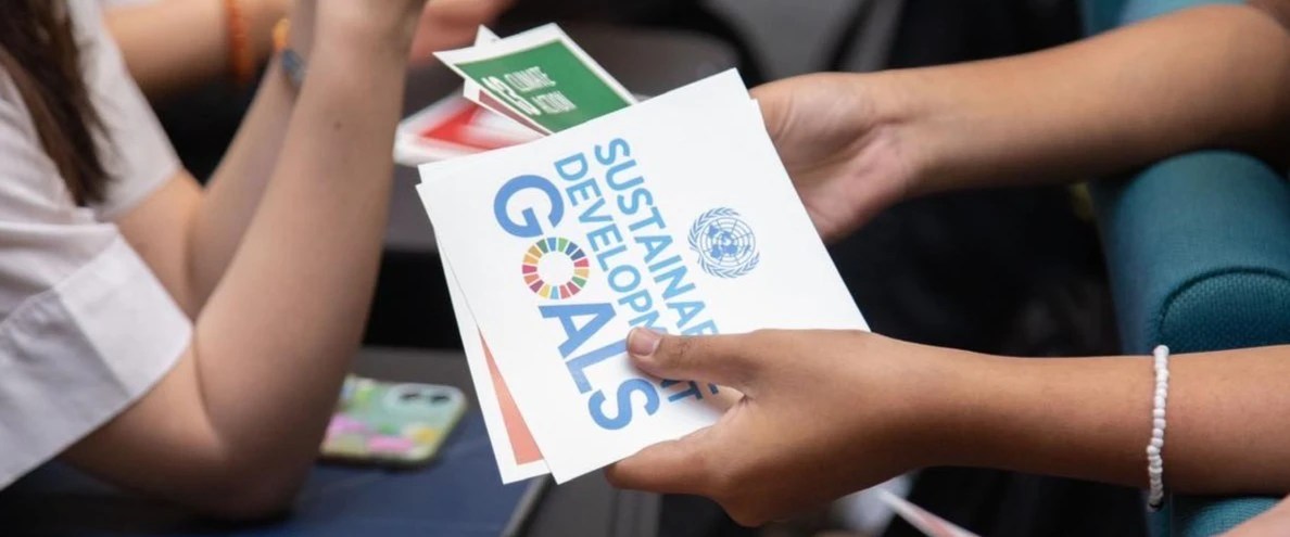 Hands holding cards with text reading "Sustainable Development Goals".